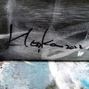 Close-up photograph of artist Ovidiu Kloska’s black signature on a monochrome abstract painting canvas with visible textured surface.